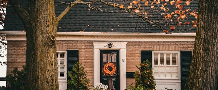 Brick house with an autumn wreath and fall leaves